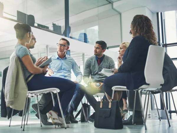 De mogelijkheden bespreken. Opname van een groep collega 's die samen praten terwijl ze in een cirkel in een kantoor zitten. — Stockfoto