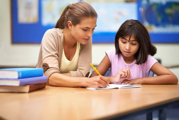 Ela é uma educadora dedicada. Tiro de uma professora ajudando seu aluno com seu trabalho na sala de aula. — Fotografia de Stock