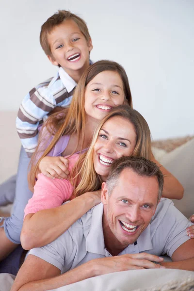 Уровни управления. Портрет счастливой молодой семьи из четырех человек, лежащей друг на друге. — стоковое фото