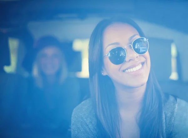 Пора отправляться в путь. Молодая женщина в солнечных очках сидит на переднем сиденье машины со своей подругой на заднем сиденье. — стоковое фото
