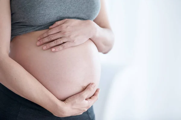 Klaar voor het moederschap. Gehakt schot van een zwangere vrouw staat in haar huis. — Stockfoto