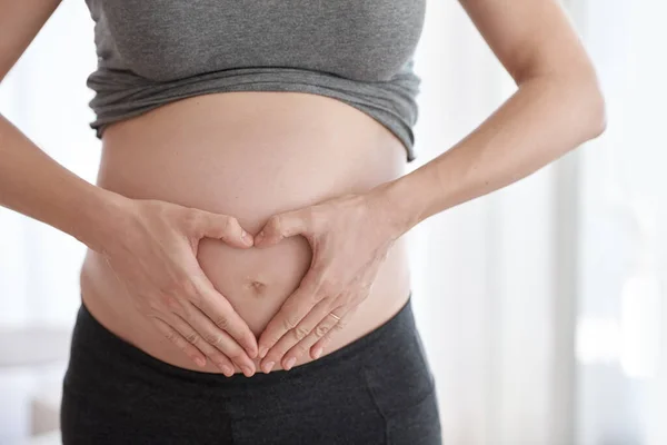 Чего ожидать, когда ждёшь. Обрезанный снимок беременной женщины, стоящей у себя дома. — стоковое фото