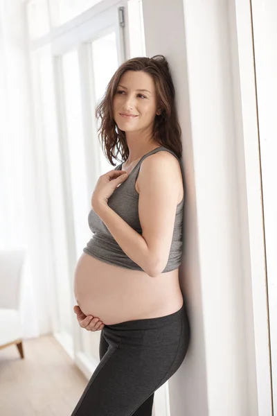 D'un jour à l'autre... Plan d'une jeune femme enceinte debout dans sa maison.. — Photo