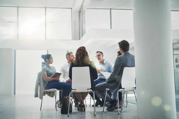 Ideeën uitwisselen. Opname van een groep collega 's die samen praten terwijl ze in een cirkel in een kantoor zitten. — Stockfoto