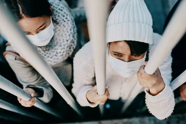 Prigionieri di una guerra virale. Girato un gruppo di giovani che indossano maschere mentre sono bloccati dietro un cancello in una città straniera. — Foto Stock