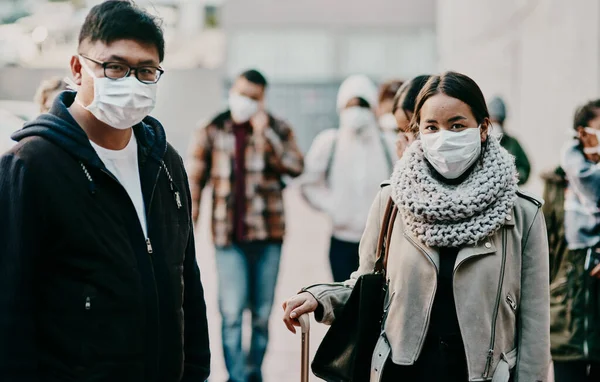 Il turismo assume un nuovo aspetto. Girato di un giovane uomo e una donna che indossano maschere mentre viaggiano in una città straniera. — Foto Stock