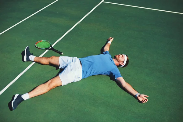 Перемога так добре себе почуває. Повнометражний знімок красивого юного тенісиста, який лежить на тенісному корті на відкритому повітрі . — стокове фото