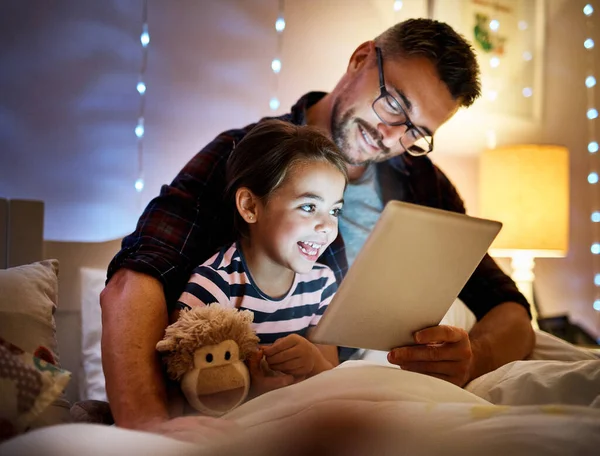 Ze houdt van verhaaltjes met papa. Gehakte foto van een vader die zijn jonge dochter een verhaaltje voorleest op een tablet. — Stockfoto