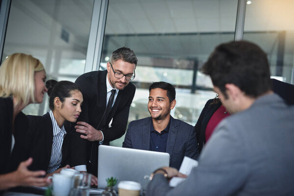 This idea will grab everybodys attention. Shot of a group of businesspeople having a meeting together over a laptop in a boardroom at the office.