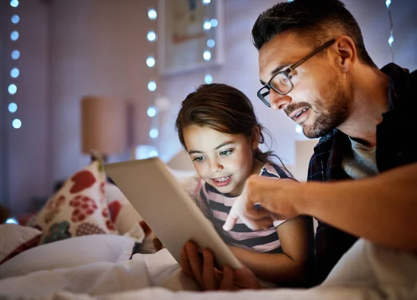 Welke zullen we vanavond lezen? Gehakte foto van een vader die zijn jonge dochter een verhaaltje voorleest op een tablet. — Stockfoto