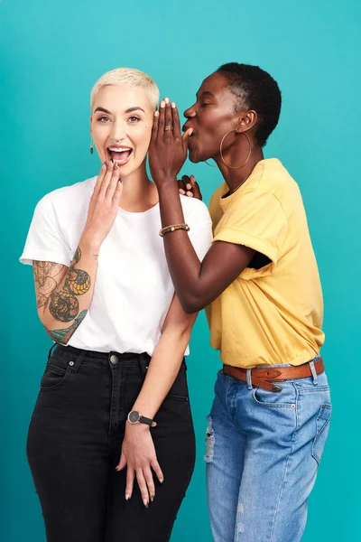 Nur für die Ohren. Studioaufnahme einer jungen Frau, die ihren Freunden vor türkisfarbenem Hintergrund ins Ohr flüstert. — Stockfoto