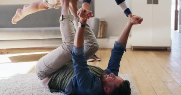 Ein bisschen Flugspaß. 4k-Videomaterial von einem jungen hübschen Ehemann, der seinen entzückenden Sohn mit seinen Füßen hochhält und im heimischen Wohnzimmer Spaß hat. — Stockvideo