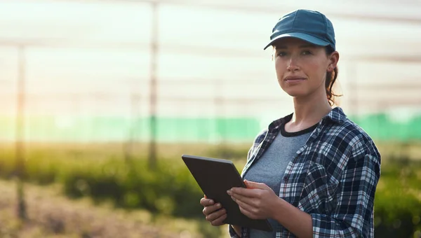 Gerir uma fazenda é um negócio sério. Retrato recortado de uma jovem agricultora atraente usando um tablet enquanto trabalhava em sua fazenda. — Fotografia de Stock