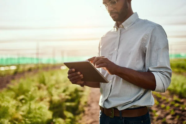 Es el futuro de la agricultura. Recortado disparo de un joven granjero guapo usando una tableta mientras trabajaba en su granja. — Foto de Stock