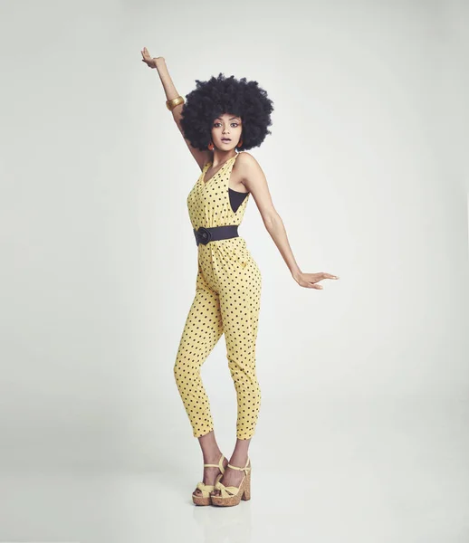 Je ressens l'ambiance des années 70. Une jeune femme portant une combinaison rétro des années 70 et prenant une pose disco en studio. — Photo