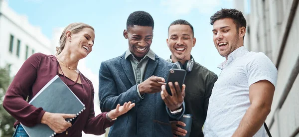Geen kantoor, geen probleem. Opname van een groep zakenmensen die samen een smartphone gebruiken tegen een stedelijke achtergrond. — Stockfoto