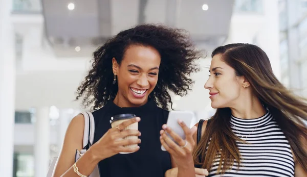 Sono i migliori colleghi. Foto ritagliata di due giovani donne d'affari che chattano e usano uno smartphone mentre camminano in un ufficio durante una pausa caffè. — Foto Stock