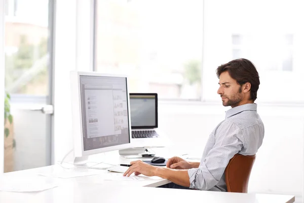 Gestalten ist ein ernstes Geschäft. Aufnahme eines gut aussehenden Mannes, der in einem Büro an einem Computer arbeitet. — Stockfoto