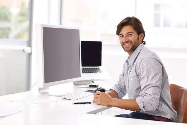 C'est facile. Un jeune homme d'affaires assis à son bureau et souriant à la caméra. — Photo