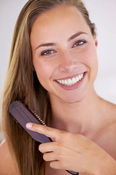 Il sorriso di una reginetta di bellezza. Una splendida donna bruna spazzolando i suoi capelli lunghi sani. — Foto Stock