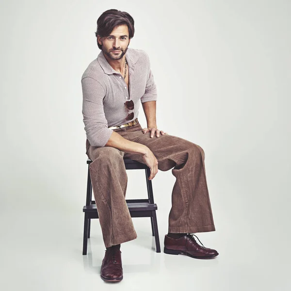 Το βλέμμα του είναι εντελώς ρετρό. Ένας όμορφος άντρας με ρούχα του '70 κάθεται στο στούντιο. — Φωτογραφία Αρχείου