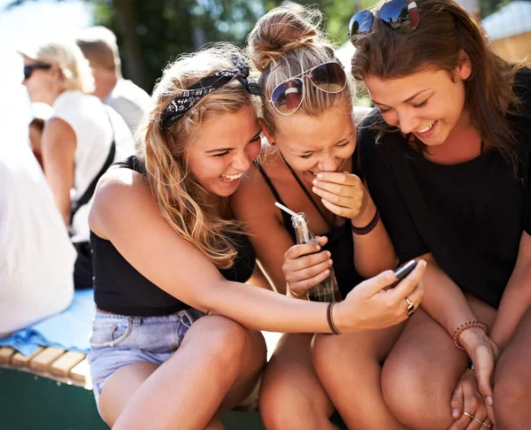 Girls getting in on the gossip. A group of three young girls huddled together and laughing while looking at a cell phone. — Stock Photo, Image