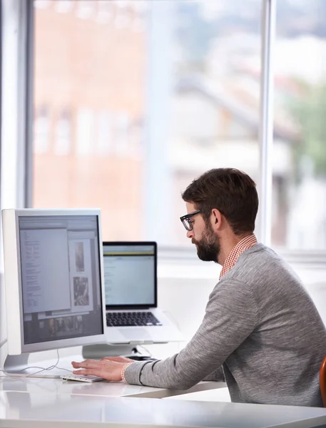 Trabajando en la próxima gran cosa. Fotografía de un joven guapo que trabaja en un ordenador en un entorno de trabajo informal. — Foto de Stock