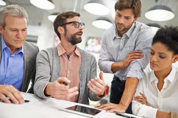 Explicando el progreso de los equipos. Fotografía de un grupo de jóvenes profesionales que trabajan en un escritorio de una oficina. — Foto de Stock