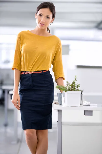 Περηφανεύεται για τον επαγγελματισμό της. Μια όμορφη νεαρή επιχειρηματίας στέκεται δίπλα στο γραφείο της στο γραφείο. — Φωτογραφία Αρχείου