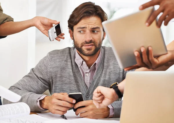 A delegação é a chave para evitar o esgotamento. Um tiro cortado de um belo homem de negócios com colegas solicitando várias coisas dele. — Fotografia de Stock