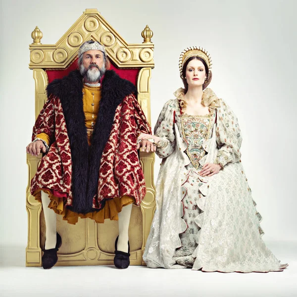 Sie regieren streng, aber fair. Studioaufnahme eines Königs und einer Königin auf Thronen. — Stockfoto