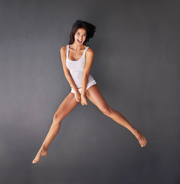 Свободно быть мной. Полнометражный снимок красивой молодой женщины, прыгающей на сером фоне. — стоковое фото