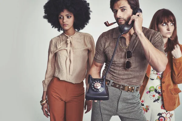 Piliçler için çok meşgul. Retro telefon kullanan yakışıklı bir adamın arkasında duran iki çekici genç hippi.. — Stok fotoğraf