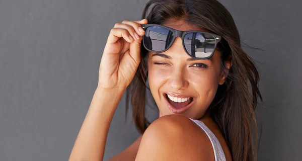 Hey you.... Shot of an attractive young woman winking at the camera while holding up her sunglasses. — Stock Photo, Image