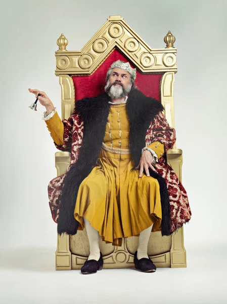 Diener kommen hierher. Studioaufnahme eines reich bekleideten Königs, der auf einem Thron sitzt. — Stockfoto