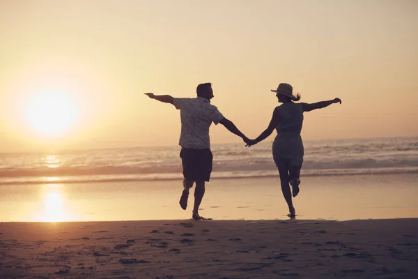 Sono andati verso il tramonto. Girato di una coppia matura che corre sulla spiaggia. — Foto Stock