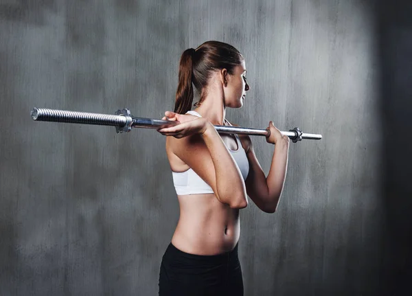 Se está haciendo más fuerte con cada entrenamiento. Una foto de una mujer haciendo ejercicio con una barra en el gimnasio. —  Fotos de Stock