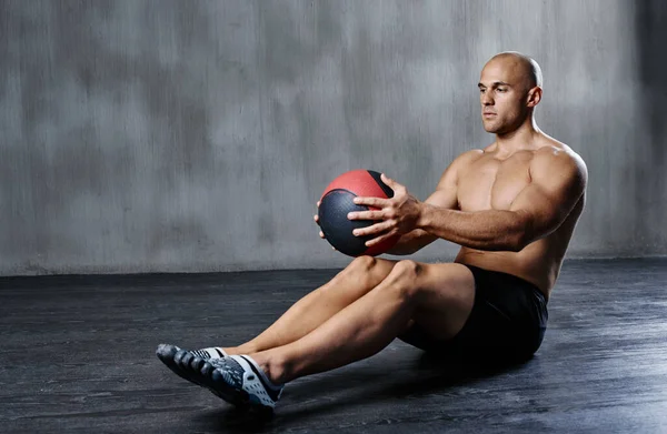 Intensificando su rutina de ejercicios. Tiro de un hombre haciendo ejercicios con una pelota de medicina en el gimnasio. — Foto de Stock