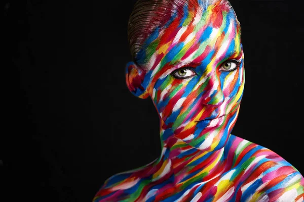 Il trucco è un'arte. Studio girato di una giovane donna in posa con vernice dai colori vivaci sul viso contro uno sfondo nero. — Foto Stock