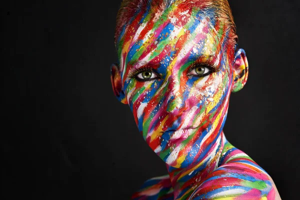Βρίσκει ομορφιά στο χρώμα. Στιγμιότυπο μιας νεαρής γυναίκας που ποζάρει με έντονα χρωματιστά χρώματα στο πρόσωπό της πάνω σε μαύρο φόντο. — Φωτογραφία Αρχείου
