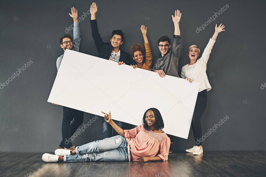 Studio shot of a diverse group of people holding up a placard against a grey background