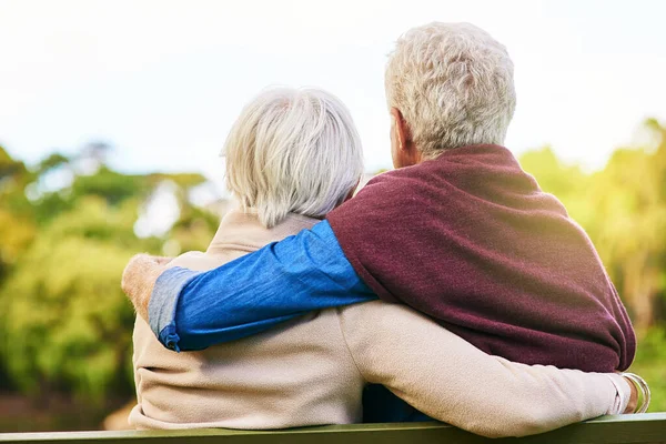 Toegewijd aan een leven van liefde. Achteraanzicht opname van een senior koppel zittend op een parkbank. — Stockfoto