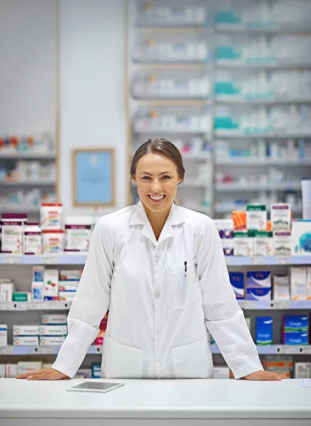 Poskytuje recepty a úsměv. Portrét atraktivního mladého lékárníka stojícího u pultu s předpisem. — Stock fotografie