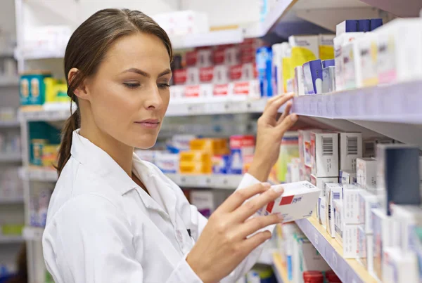 Encontrar la medicación adecuada. Fotografía de un atractivo joven farmacéutico comprobando el stock en un pasillo. — Foto de Stock