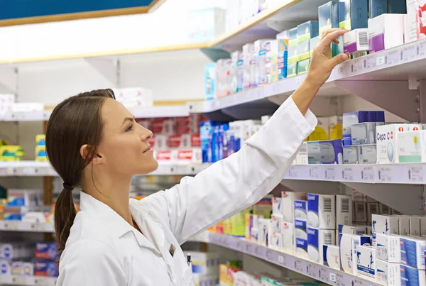 Sabe lo que necesitan sus clientes. Fotografía de un atractivo joven farmacéutico comprobando el stock en un pasillo. — Foto de Stock