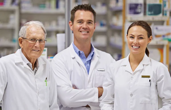 A lehető legjobb szolgáltatást nyújtom. A pultnál álló három gyógyszerész portréja. — Stock Fotó
