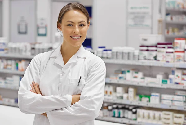 Cumprimentando cada cliente com sorriso. Retrato de um jovem farmacêutico atraente em pé no balcão de receitas. — Fotografia de Stock