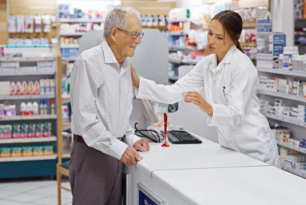 Asegurar que los clientes estén informados. Inyección de un joven farmacéutico ayudando a un cliente mayor en el mostrador de prescripción. — Foto de Stock