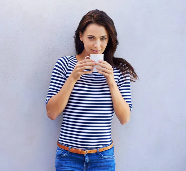 Nå er det en god øl. Portrett av en attraktiv kvinne som holder en kaffekopp mot grå bakgrunn. – stockfoto