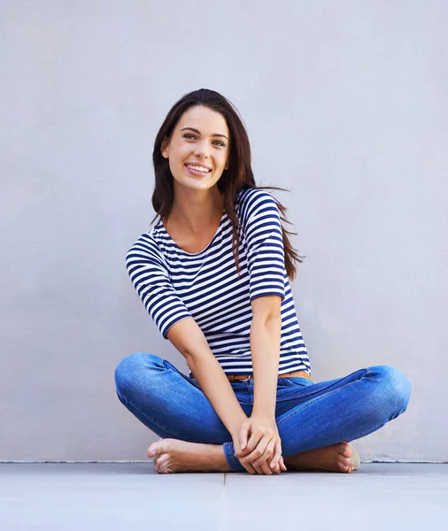 Feliz de ser yo. Foto completa de una hermosa joven sentada con las piernas cruzadas en el suelo. — Foto de Stock